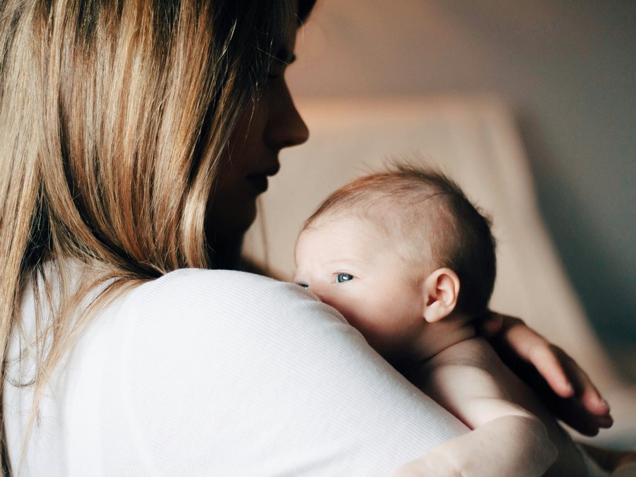 A mother holding her newborn against her shoulder